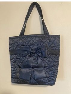 a blue purse hanging on the wall with a black ribbon tied around it's front pocket