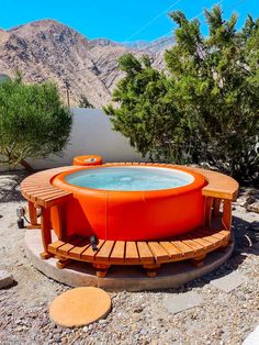 an outdoor hot tub in the middle of a rocky area with mountains in the background