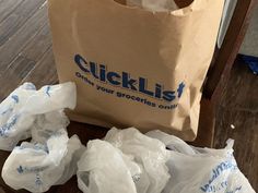 a brown paper bag sitting on top of a wooden floor next to bags filled with plastic