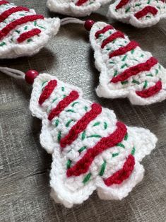 crocheted christmas tree ornaments with red and green trimmings on a table