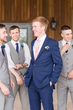 a group of men standing next to each other in front of a wooden wall wearing suits and ties