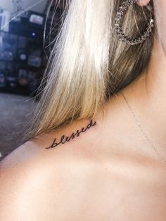 the back of a woman's neck with words written on her left shoulder and behind her ear