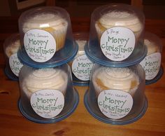 four plastic containers filled with cupcakes on top of a wooden table