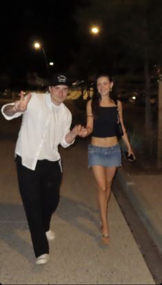 a man and woman walking down the street at night