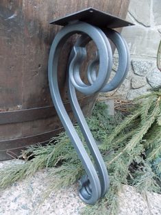 a metal object sitting on the ground next to a wooden barrel filled with pine needles