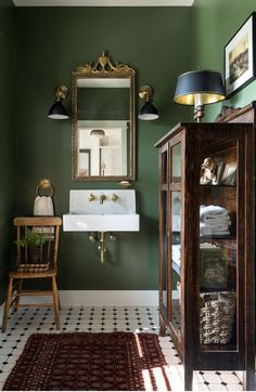 a bathroom with green walls and white tile on the floor, along with a wooden cabinet