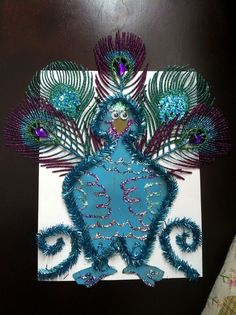 a peacock made out of paper with feathers on it's back, and the tail is