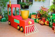 a toy train with a potted plant in the center and presents on the ground next to it