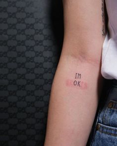 a woman's arm with the word i'm ok tattooed on her left arm