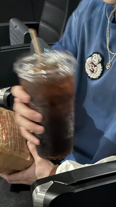 a man is holding a drink in his hand while sitting on the seat of an airplane