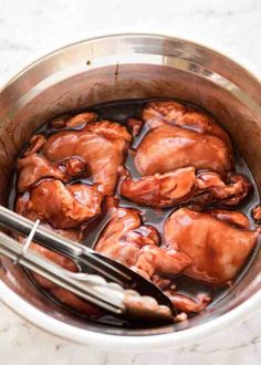 the meat is being cooked in the pot with tongs