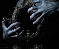 two hands holding a mirror in the dark