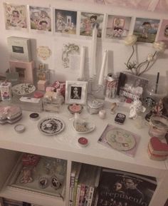 a white table topped with lots of books and other items next to a wall covered in pictures