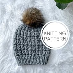 a gray knitted hat with a brown pom - pom on the top