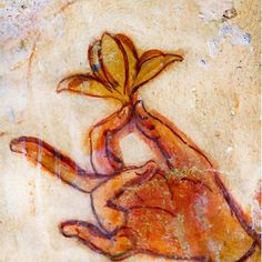 a painting on the side of a rock with a flower in it's hand