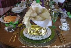 the table is set with gold and green plates, silverware, and napkins