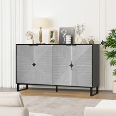 a black and white sideboard in a living room next to a potted plant