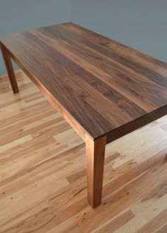 a large wooden table sitting on top of a hard wood floored floor next to a wall