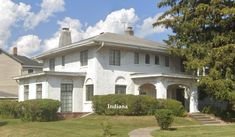 a large white house sitting on top of a lush green field