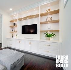 a living room with white cabinets and a flat screen tv mounted on the wall above it