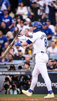 a baseball player holding a bat on top of a field in front of a crowd