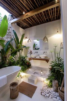 a bathroom with plants and rocks in the floor, along with a bathtub surrounded by greenery