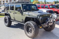 the jeep is parked on the side of the road with other cars in the background