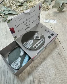 an open box with two plates in it on a wooden table next to some flowers