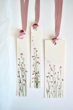 two tags with pink ribbons hanging from them on a white wall next to each other