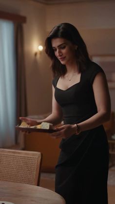 a woman standing in front of a table holding a piece of food