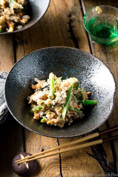 a bowl filled with food next to chopsticks on top of a wooden table