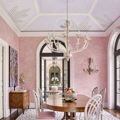 a dining room with pink walls and white trim on the ceiling is featured in this magazine