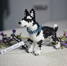 a beaded black and white dog figurine next to flowers