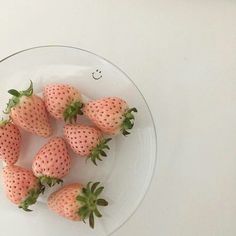 a glass plate filled with strawberries on top of a table