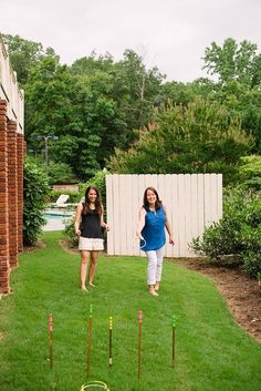 two women walking in the grass near some croquets