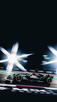 a racing car driving on a race track at night with motion blurs behind it