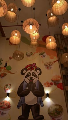 a large panda bear mural on the side of a wall with lights hanging from it's ceiling