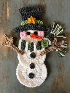 a crocheted snowman ornament hanging on a wall