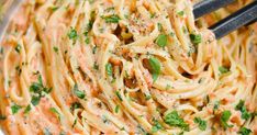 a close up of a pasta dish with carrots and parsley