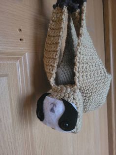 a crocheted purse hanging from a door handle with a face on the front