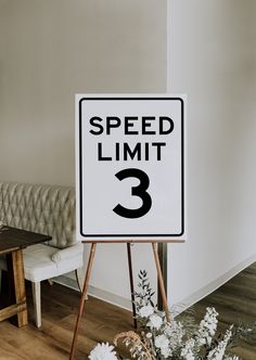 a speed limit 3 sign sitting on top of a wooden easel next to a couch