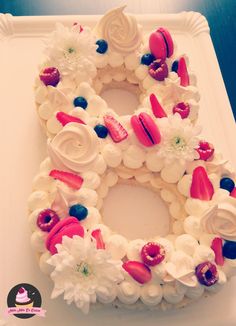 a cake shaped like the letter o with flowers and berries on it's side