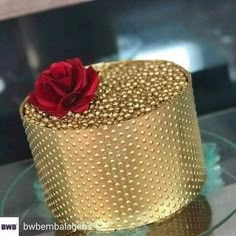 a gold cake with a red rose on top