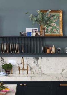 a kitchen with marble counter tops and gold faucets on the shelf above it