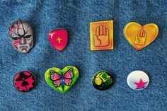 six buttons with different designs on them sitting in the shape of heart and hand symbols