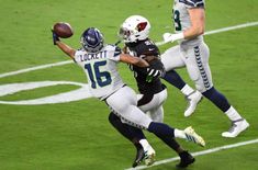 two football players are jumping in the air to catch a ball while another player tries to block it