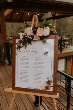 a sign with flowers and greenery on it that says welcome to the couple at their wedding