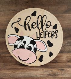 a wooden sign that says hello heifers with a cow's face painted on it