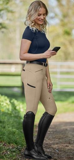 a woman in riding gear is looking at her phone