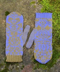 two mittens sitting on top of a moss covered rock